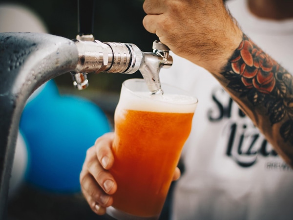 a hand of the bartender tapping a cold beer in glass