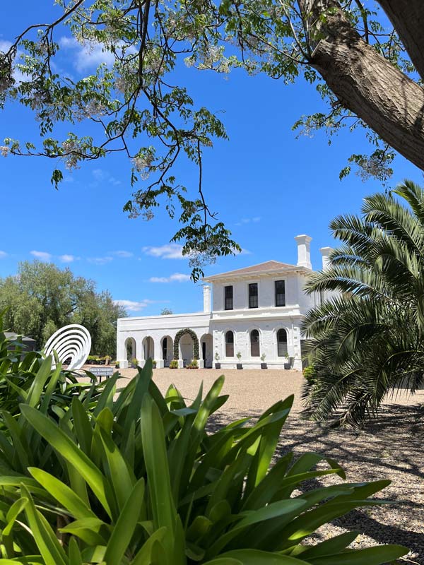 a white structure surrounded by lush greenery outside The Station at Kapunda