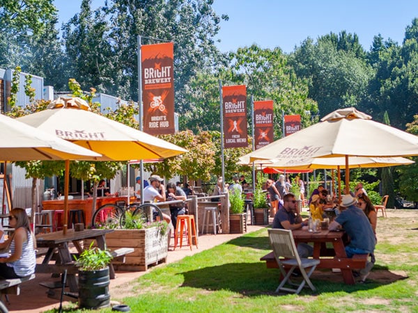 people drinking and dining under sun umbrellas outside Bright Brewery