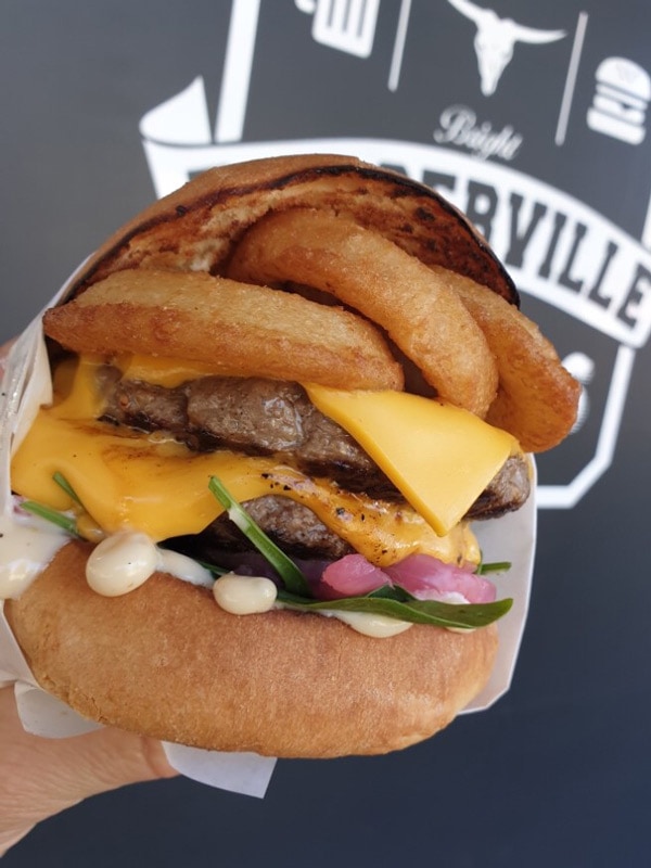 a close-up shot of a hand holding a big burger at Burgerville, Bright