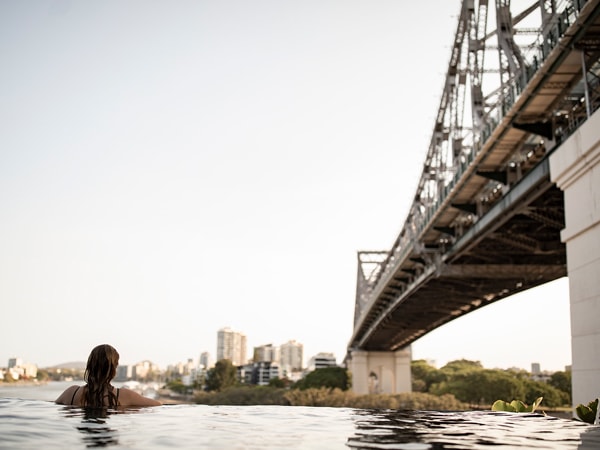 Wanita berenang di kolam renang di Crystalbrook Vincent di bawah Story Bridge di Brisbane