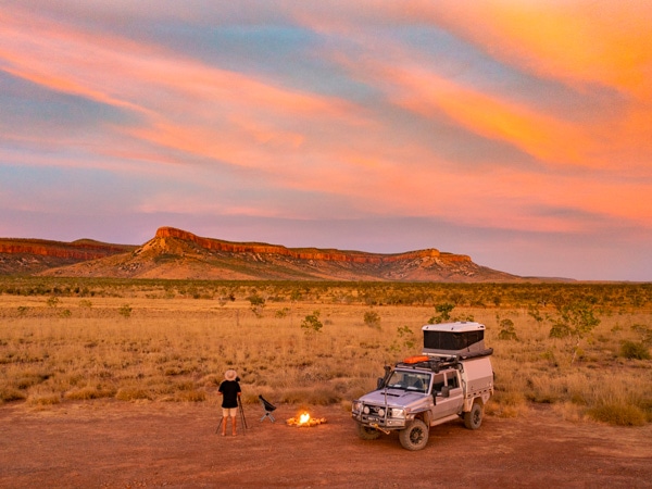 a man setting up a bonfire outside his 4WD in El Questro