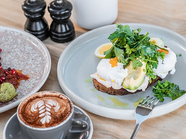 Eggs and avocado on toast and a cup of coffee