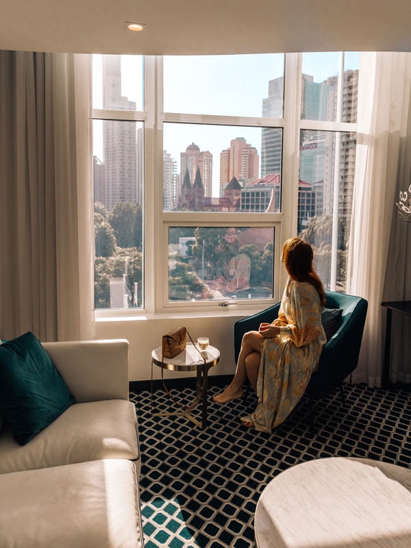 Seorang wanita duduk di dekat jendela di hotel mewah Ovolo Inchcolm di Brisbane