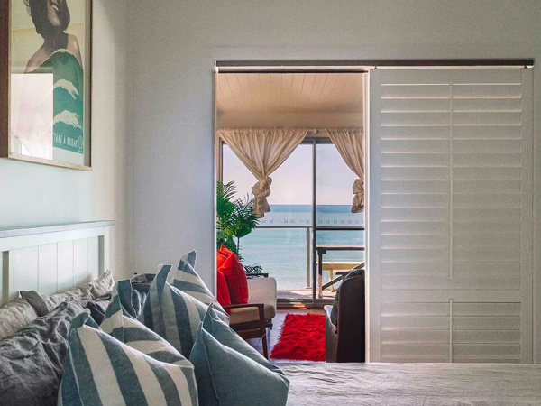 the bedroom with windows that open up to sea views at Pacific Lodge