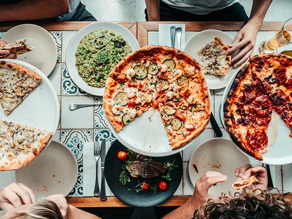 Sebuah meja berisi pizza dan pasta 
