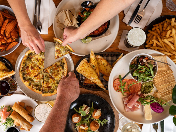 hands grabbing pizza slices at Seaview Tavern