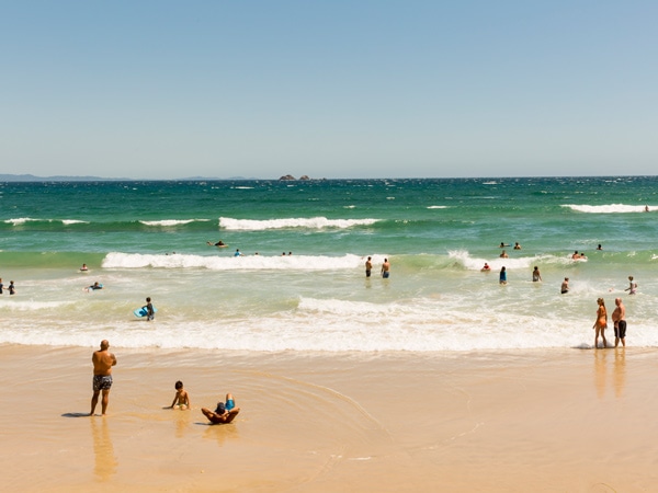 Orang-orang menikmati hari musim panas di Pantai Wategos, Teluk Byron.