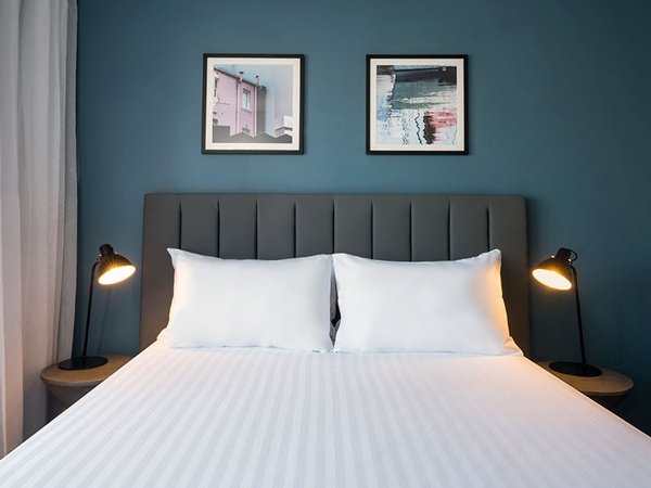 a bed with white sheets at Travelodge Hotel Hobart