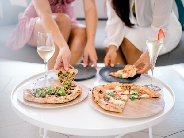 two women enjoying cocktails and pizza at Aviary Rooftop Bar