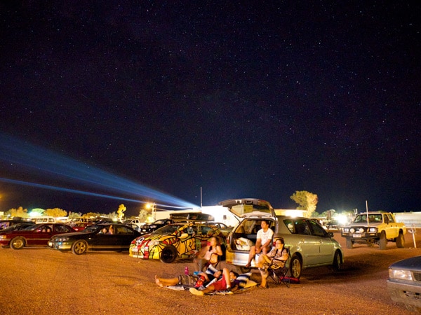 a family chilling outside their vehicle under the stars at the Coober Pedy Drive-In Theatre