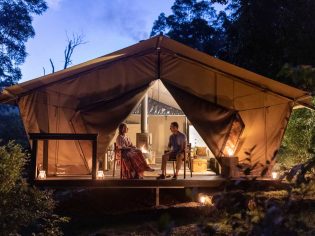 a couple inside a luxurious glamping tent at Nightfall