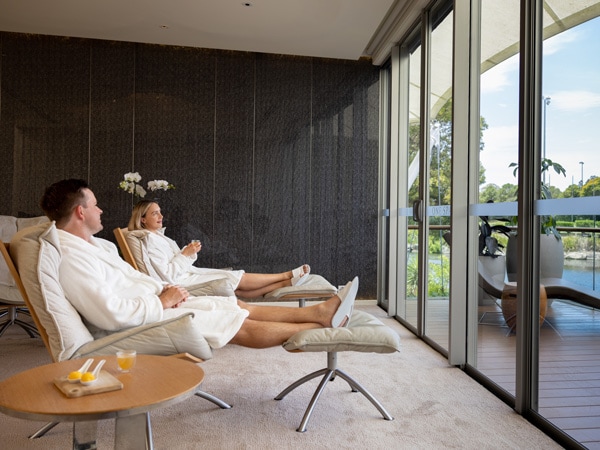 a couple in robe sitting while gazing out the glass window