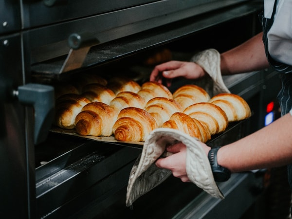 a baker getting freshly baked bread out of the oven at Silo Bakery