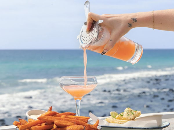 pouring a drink into a glass on the beach at Burleigh Pavilion, Burleigh Heads