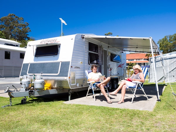 a couple sitting outside their caravan at Burleigh Beach Tourist Park