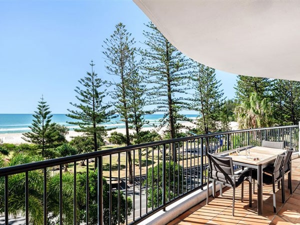 a balcony with a dining table and chairs overlooking the beach at Mantra Coolangatta Beach