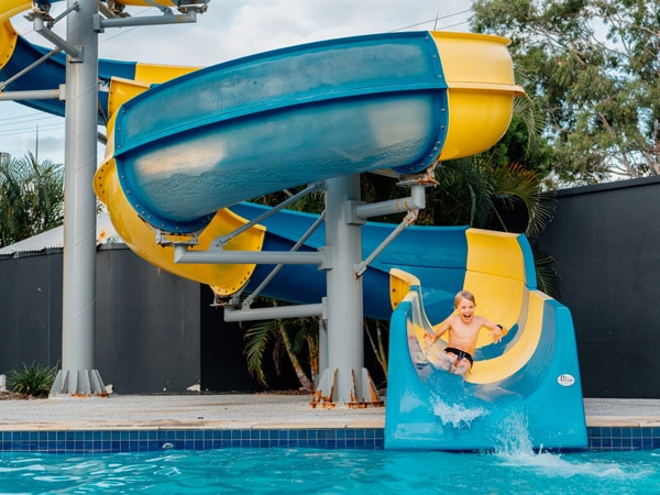 a kid on a slide by the poolside