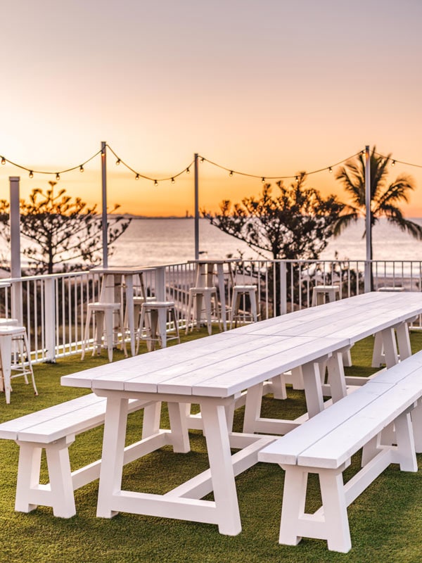 a long picnic table with chairs at the roof deck in Pink Hotel