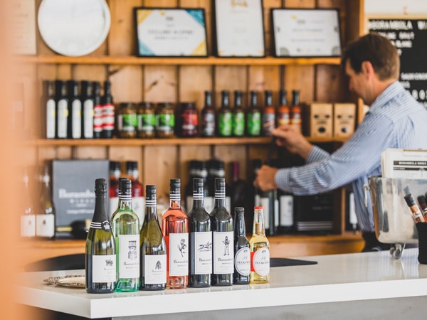 a bartender arranging a stack of wine bottles at the bar counter of Borambola Wines