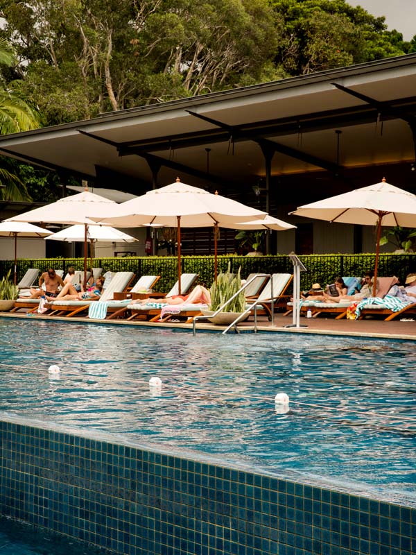 an outdoor pool with umbrellas and sun loungers at Crystalbrook Byron