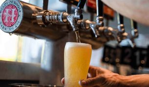 a hand holding a glass of beer on tap