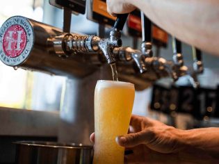 a hand holding a glass of beer on tap