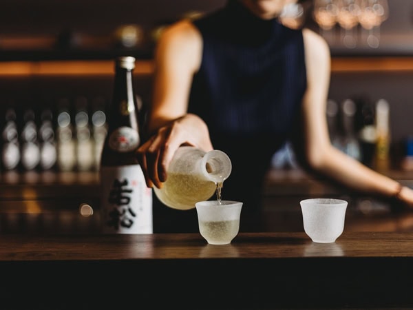 pouring Japanese alcohol into a cup at Mu Omakase, Canberra