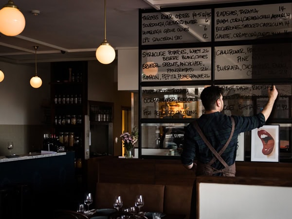 a staff writing on the glass walls at Onzieme Restaurant, Canberra