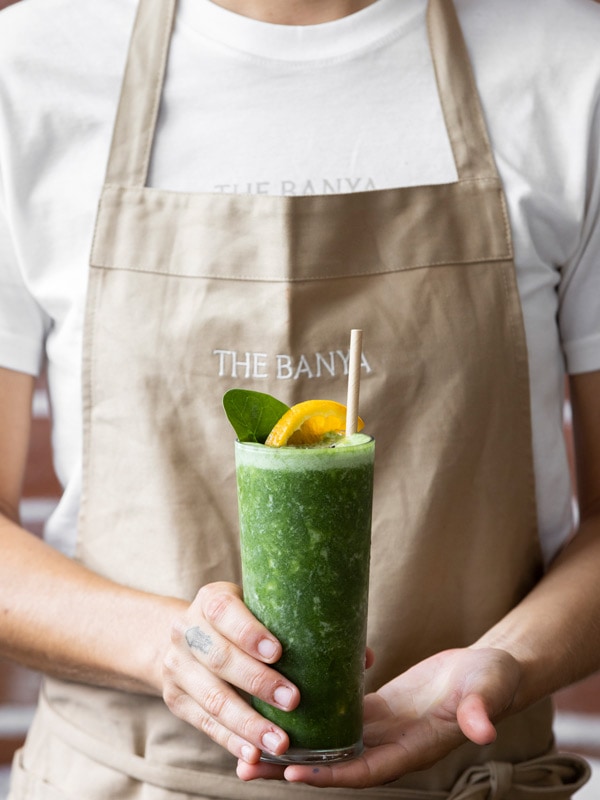 a waitress holding a green juice at The Banya