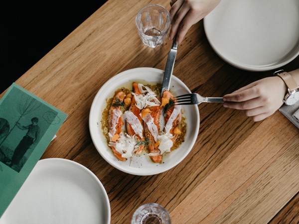 a hand holding a fork and a knife while slicing a dish at Rebel Rebel, Canberra