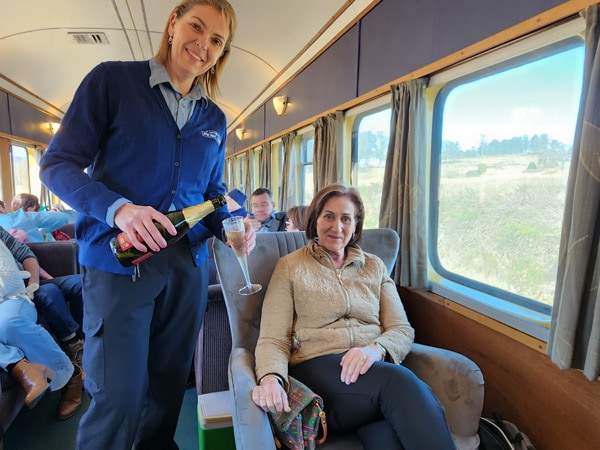 a staff serving champagne to one of the passengers inside Kiama Picnic Train