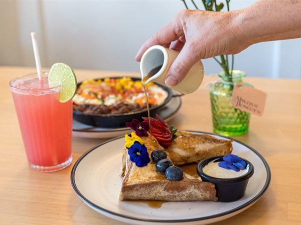 pouring sweet syrup over a breakfast plate at Frida’s Cantina, Kiama restaurants