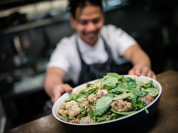 a chef holding a dish at Muse, East Hotel Canberra
