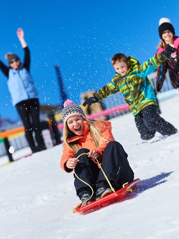 a woman sliding down the snow at Toboggan Parks