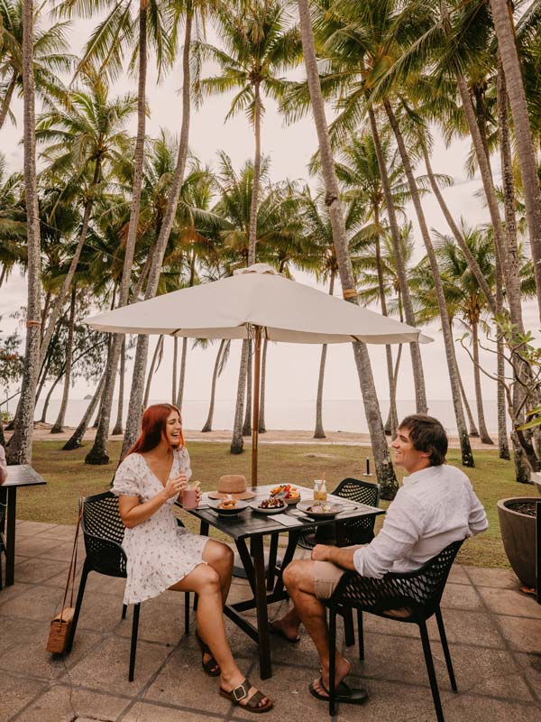 a couple dining under palm trees at Nu Nu Restaurant, Palm Cove