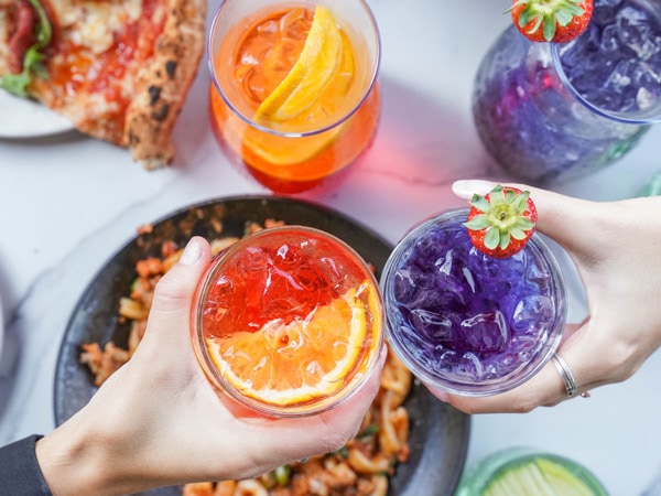 a table-top view of two hands holding drinks at 400 Gradi Bottomless