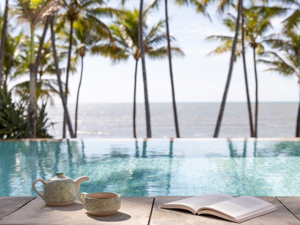 an open book with a cup of tea in the pool area at L.M Spa, Palm Cove