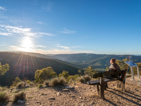 a man sitting on a bench at sunrise, Beaufoy Merlin Lookout