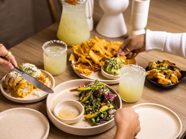 hands reaching for food on the table at Bottomless Sunday arvo sessions at El Rey, Cronulla