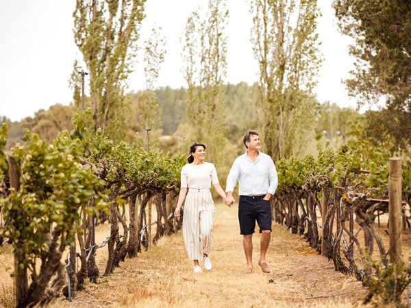 a couple walking along the Helm Wines vineyard in Murrumbateman