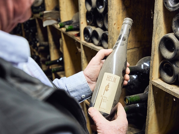 Winemaker Ken Helm holding a bottle of wine in the Helm Wines cellar door, Murrumbateman