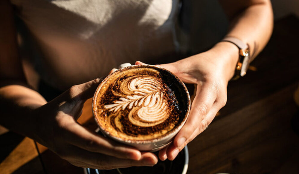 a person holding a cup of coffee at The Hungry Monkey, Kiama cafe