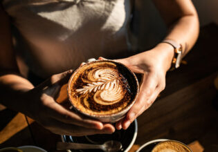 a person holding a cup of coffee at The Hungry Monkey, Kiama cafe