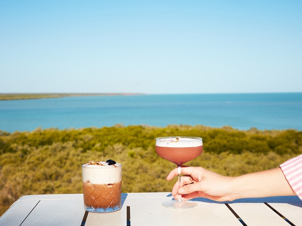 a hand holding a glass of cocktail at Mangrove Hotel
