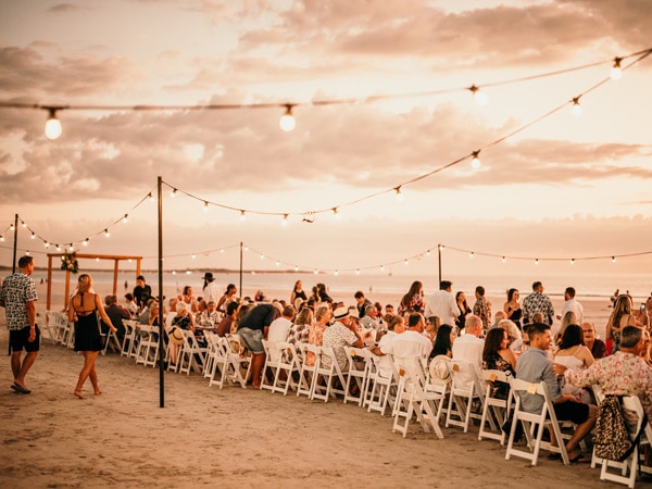 people having dinner on the beach at the long table