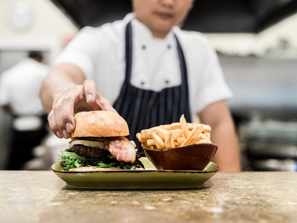 a chef preparing burger and fries at Vivo Palm Cove