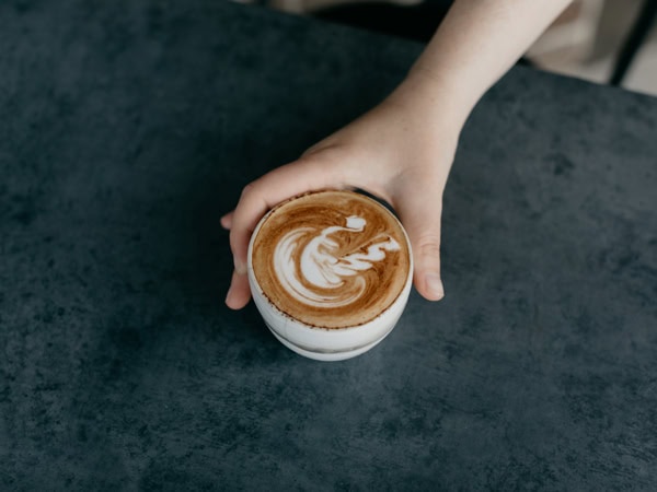 a hand holding a cup of latte at Intra, Canberra