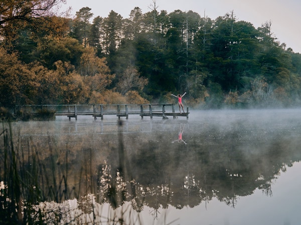 a woman standing on the edge of the Lake Daylesford Jetty and Bridge