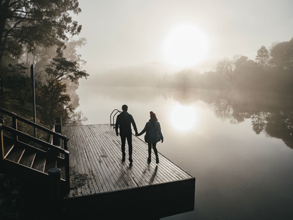 a couple walking over the Lake Daylesford Jetty and Bridge